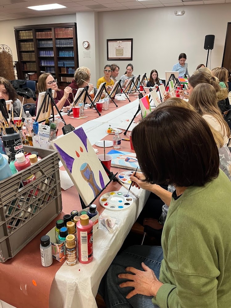Large group painting class with easels and canvases