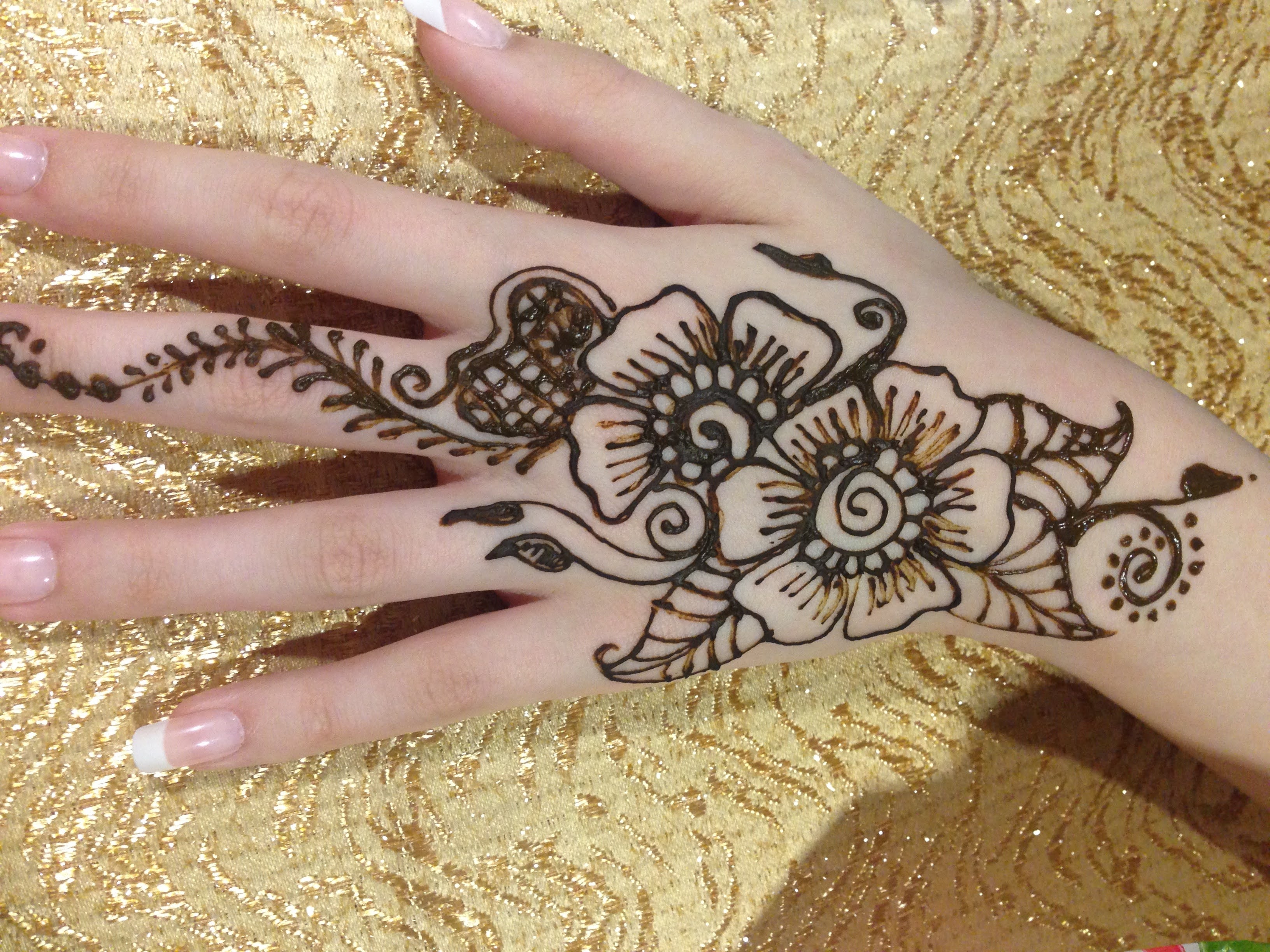 Floral henna design on hand against gold background